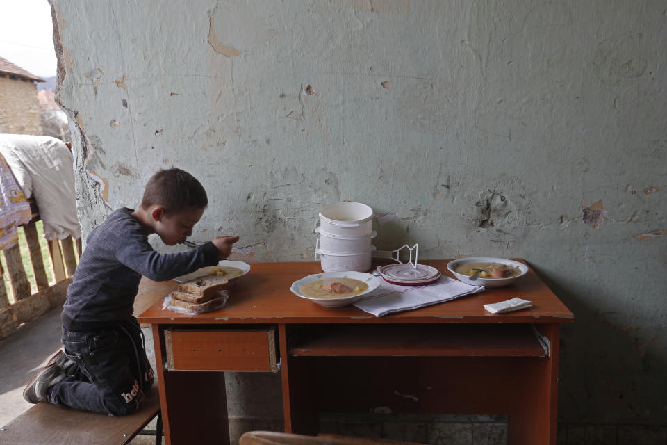 Milan Bastyur, a 4 year old Hungarian Roma child, eats lunch outside his family's home in Bodvaszilas, Hungary, Monday, April 12,2021. Many students from Hungary's Roma minority do not have access to computers or the internet and are struggling to keep up with online education during the pandemic. Surveys show that less than half of Roma families in Hungary have cable and mobile internet and 13% have no internet at all. (AP Photo/Laszlo Balogh)