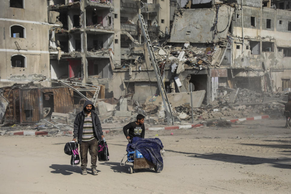 Palestinians walk through destruction in Gaza City on Friday, Nov. 24, 2023, as the temporary ceasefire between Israel and Hamas took effect. (AP Photo/Mohammed Hajjar)