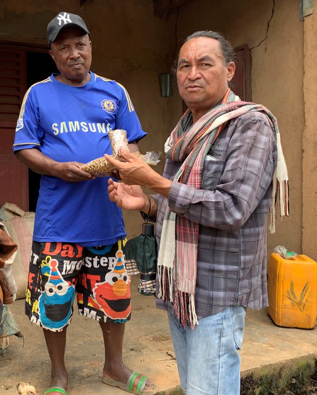 Randriamampionina, farmer and coffee grower and Jacques Ramarlah, a farmer and agricultural entrepreneur hold coffee berries during harvest in Amparaky village in Ampefy town of Itasy region