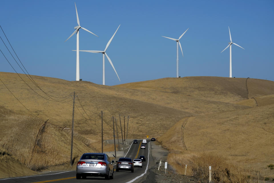 FILE - Vehicles move down Altamont Pass Road with wind turbines in the background in Livermore, Calif., Aug. 10, 2022. The past year saw major governments around the world green lighting ambitious renewable energy policies. The United States signed into law its Inflation Reduction Act. (AP Photo/Godofredo A. Vásquez, File)