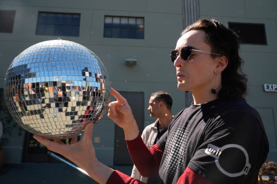 Robb Godshaw uses a mirrored ball to project images of the total solar eclipse onto an exterior wall of the Exploratorium in San Francisco, Monday, April 8, 2024. (AP Photo/Eric Risberg)