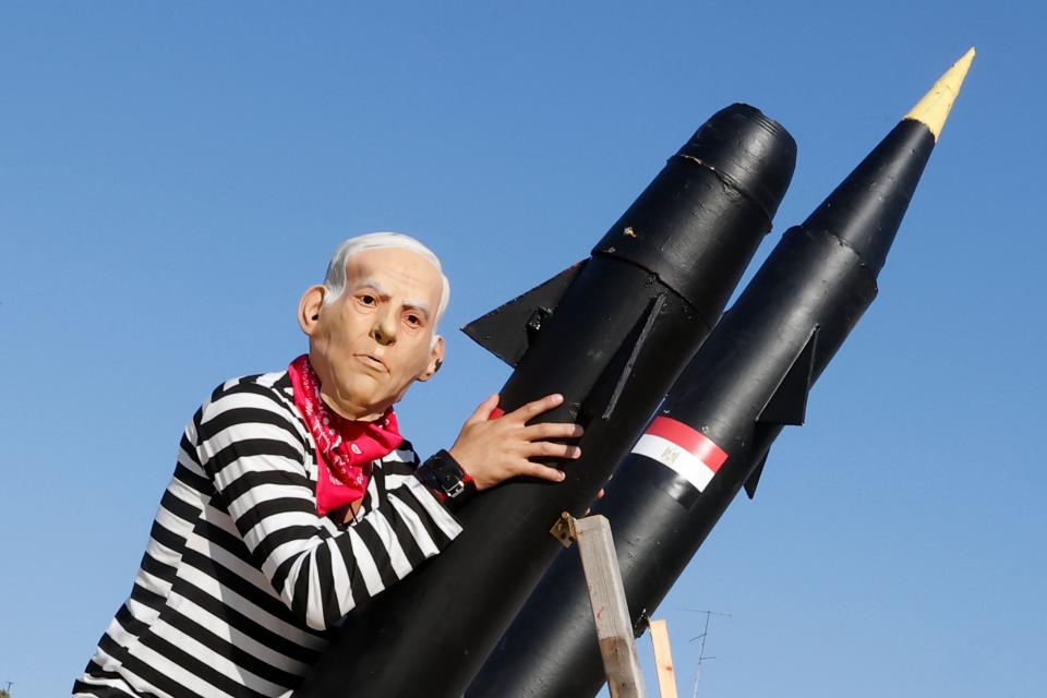 An Israeli protester wearing a mask of Netanyahu holds a mock rocket during a demonstration in 2020 (AFP/Getty)