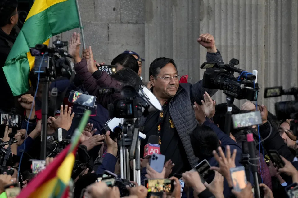 Bolivian President Luis Arce raises a clenched fist surrounded by supporters and media, outside the government palace in La Paz, Bolivia, Wednesday, June 26, 2024. Armored vehicles rammed the doors of Bolivia's government palace Wednesday in an apparent coup attempt against Arce, but he vowed to stand firm and named a new army commander who ordered troops to stand down. (AP Photo/Juan Karita)