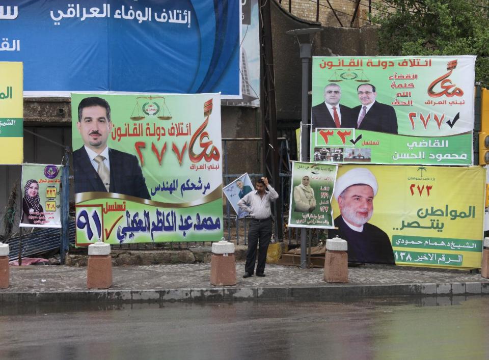 In this photo taken on April 14, 2014, an Iraqi man scratches his head as he stands amid campaign posters in Baghdad, Iraq. The vibrant posters promise jobs, prosperity and security coming from Iraq’s first parliamentary elections since U.S. troops withdrew from the country, but so far, voters have only dim hopes as sectarian bloodshed rages unstopped. (AP Photo/Khalid Mohammed)
