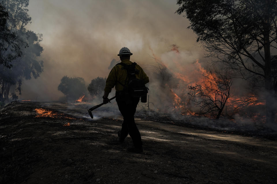 A firefighter prepares to put out hotspots while battling the Silverado Fire, Monday, Oct. 26, 2020, in Irvine, Calif. The fast-moving wildfire forced evacuation orders for 60,000 people in Southern California on Monday as powerful winds across the state prompted power to be cut to hundreds of thousands to prevent utility equipment from sparking new blazes. (AP Photo/Jae C. Hong)