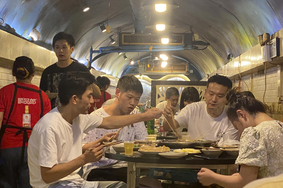 Customers eat hotpot in a hotpot restaurant located in a converted WWII-era air raid shelter in southwestern China's Chongqing Municipality, Saturday, Aug. 20, 2022. The city of Chongqing, dubbed one of China's four "furnace" cities, is known for both soaring temperatures and spicy cuisine - notably its hotpot, a peppery bubbling tabletop broth into which diners dunk bite-size pieces of food to cook and eat. (AP Photo/Mark Schiefelbein)