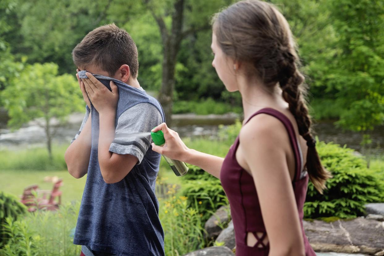 teenagers spraying insect repellant on each other in summer nature