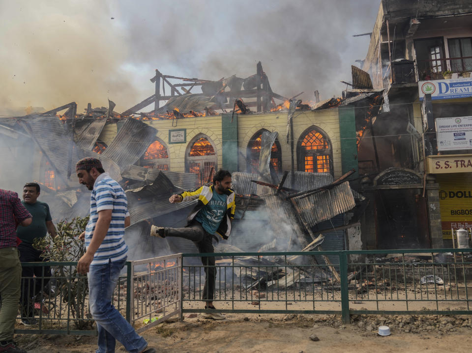 Civilians work to extinguish a fire in Srinagar, Indian controlled Kashmir, Monday, June 24, 2024. A mosque and some buildings were damaged in the fire. Some people were injured in this incident. (AP Photo/Mukhtar Khan)