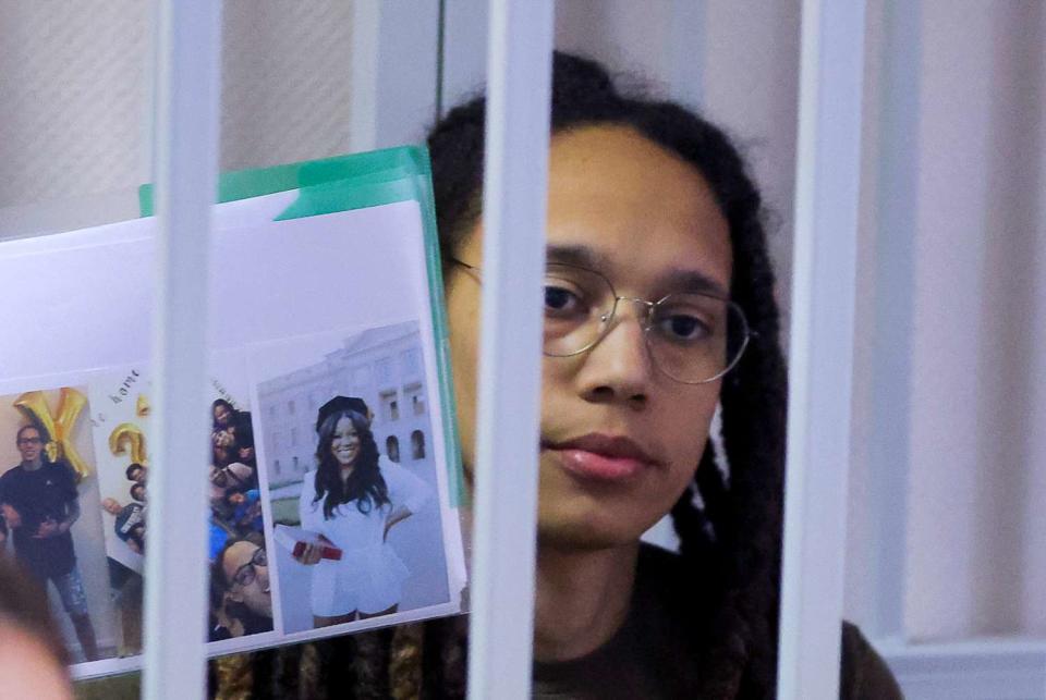 US basketball player Brittney Griner holds photos inside a defendants' cage before a court hearing during her trial on charges of drug smuggling, in Khimki, outside Moscow on August 2, 2022. - Griner was detained at Moscow's Sheremetyevo airport in February 2022 just days before Moscow launched its offensive in Ukraine. She was charged with drug smuggling for possessing vape cartridges with cannabis oil. Speaking at the trial on July 27, Griner said she still did not know how the cartridges ended up in her bag.