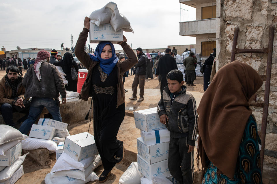 A displaced woman carries a box of humanitarian aid supplied by an NGO in Idlib, Syria, on Feb. 19, 2020. | Burak Kara—Getty Images