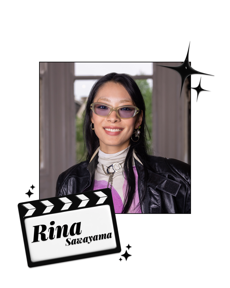 Rina Sawayama smiling in a leather jacket and purple sunglasses