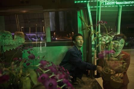 People carry flowers to decorate the lobby of a hotel in Pyongyang late October 7, 2015.REUTERS/Damir Sagolj