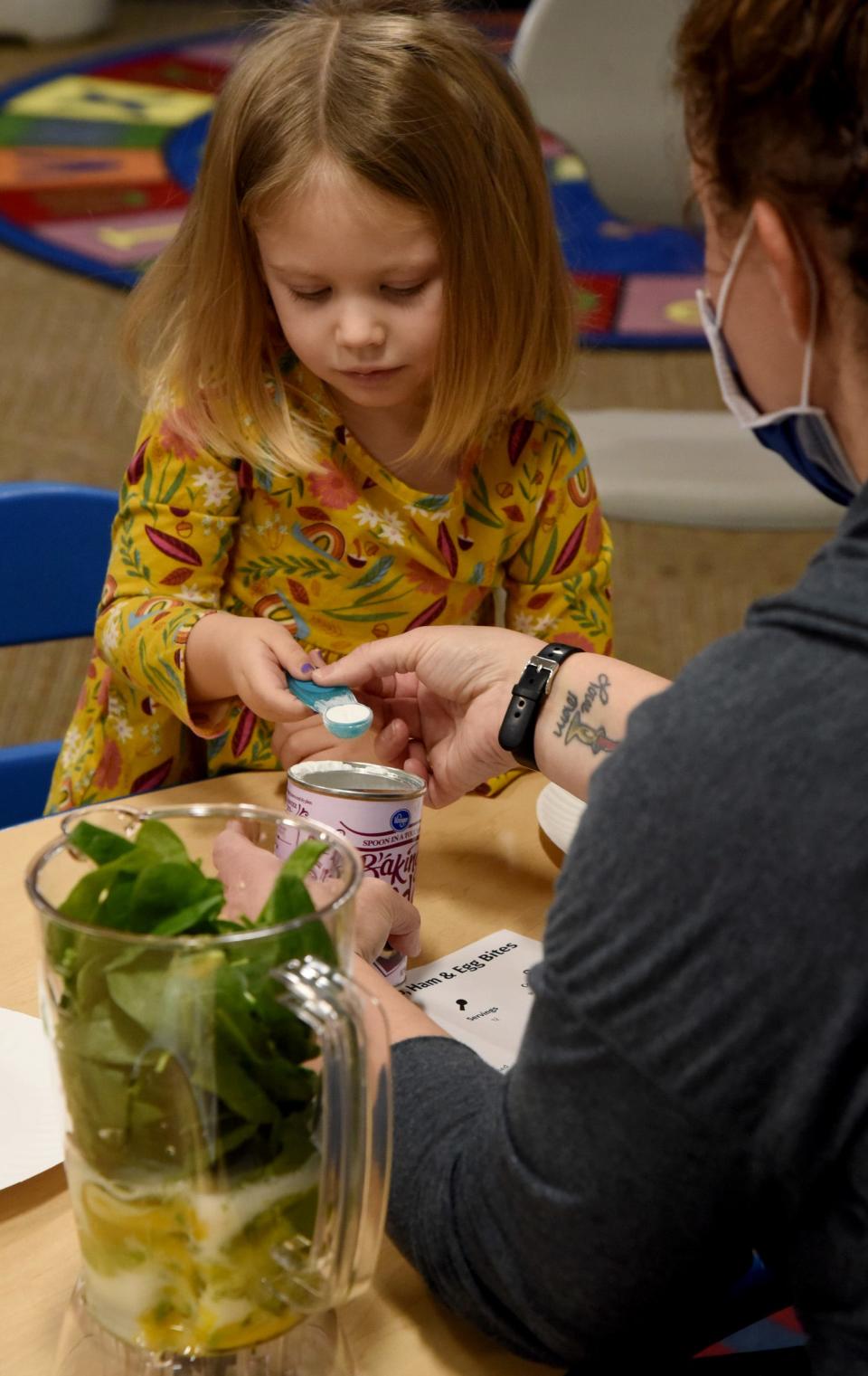 Preschooler Ellie Nowitzke, 3, measures out baking powder.