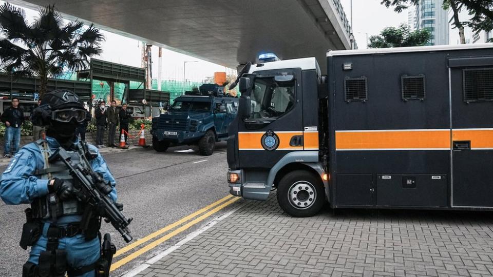 A security personnel stands guard as a prison van that is believed to carry media mogul Jimmy Lai, founder of Apple Daily, leaves the West Kowloon Magistrates" Courts on the day of the national security trial, in Hong Kong, China December 18, 2023.