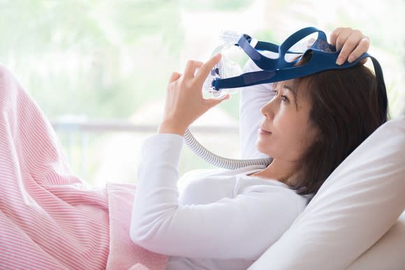 Woman putting sleep apnea mask on