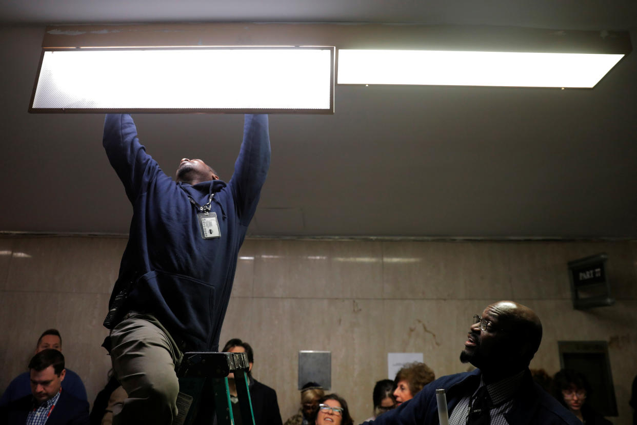 Building maintenance workers change a light bulb near a courtroom in the Manhattan borough of New York City,