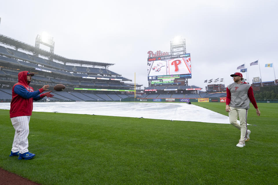 Philadelphia Phillies' Spencer Turnbull, right, tosses a football to Bullpen Catcher/Assistant Catching Coach Hector Rabag, left, prior to the baseball game against the Cincinnati Reds, Wednesday, April 3, 2024, in Philadelphia. (AP Photo/Chris Szagola)