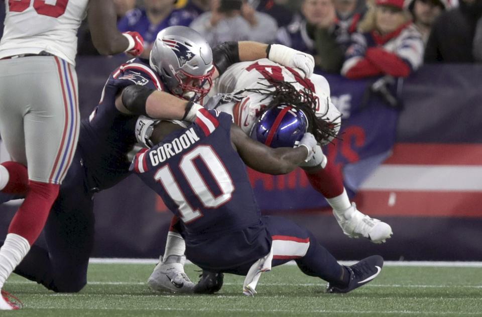 New York Giants linebacker Markus Golden, right, pulls free from New England Patriots center Ted Karras, left, and wide receiver Josh Gordon (10) after recovering a fumble in the first half of an NFL football game, Thursday, Oct. 10, 2019, in Foxborough, Mass. Golden scored a touchdown on the play. (AP Photo/Charles Krupa)