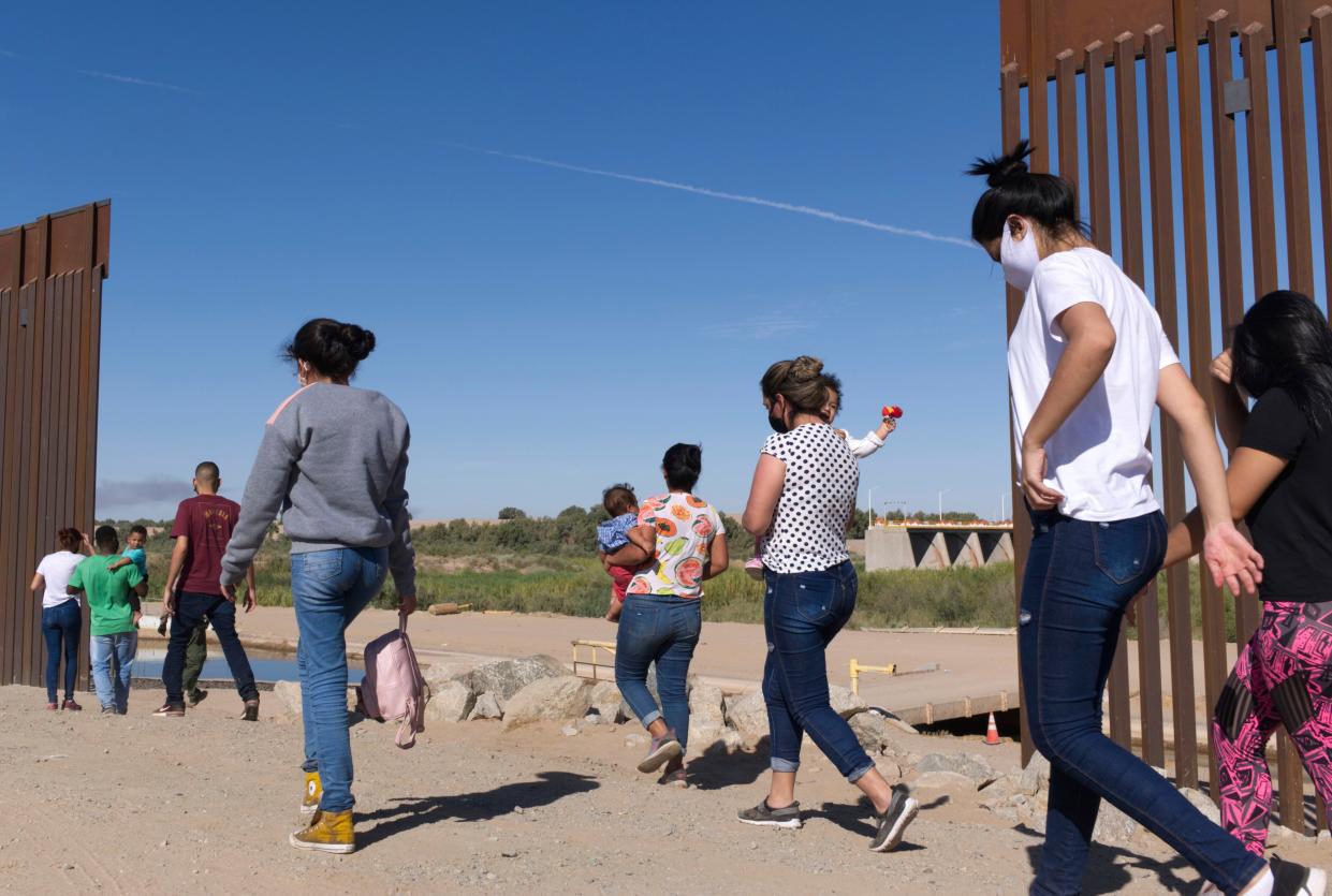 FILE - A group of Brazilian migrants make their way around a gap in the U.S.-Mexico border in Yuma, Ariz., seeking asylum in the U.S. after crossing over from Mexico, June 8, 2021. Two Republican border-state governors who are investing billions of dollars on immigration enforcement and hours at the podium blasting the Biden administration policies have found two unlikely allies: Democratic mayors Muriel Bowser of Washington, D.C., and Eric Adams of New York. The mayors' recent overtures for federal aid is a response to Texas and Arizona busing migrants away from the border, a months-old practice that has been long on political theater and short on practical impact. (AP Photo/Eugene Garcia, File)