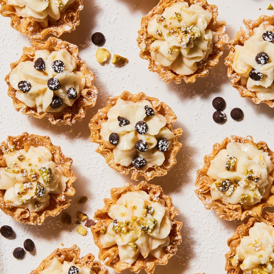 individual cannoli bites topped with chocolate chips, crushed pistachio and powdered sugar