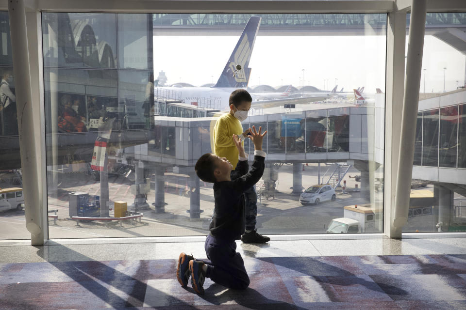 A boy wearing a face mask plays with another boy at Hong Kong International Airport in Hong Kong, Tuesday, Jan. 21, 2020. Face masks sold out and temperature checks at airports and train stations became the new norm as China strove Tuesday to control the outbreak of a new coronavirus that has reached four other countries and territories and threatens to spread further during the Lunar New Year travel rush. (AP Photo/Ng Han Guan)