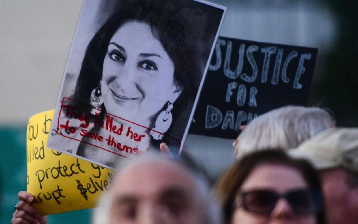 Protesters holding a photo of killed reporter Daphne Caruana Galizia gather outside Parliament in Valletta, Malta - AFP