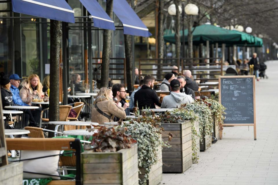 People sit at an outdoor restaurant in Kungstradgarden park, Stockholm (via REUTERS)