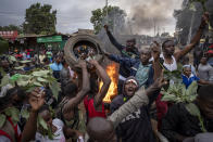 Supporters of presidential candidate Raila Odinga throw tires onto a fire as they protest in the Kibera neighborhood of Nairobi, Kenya Monday, Aug. 15, 2022. After last-minute chaos that could foreshadow a court challenge, Kenya's electoral commission chairman has declared Deputy President William Ruto the winner of the close presidential election over five-time contender Raila Odinga. (AP Photo/Ben Curtis)