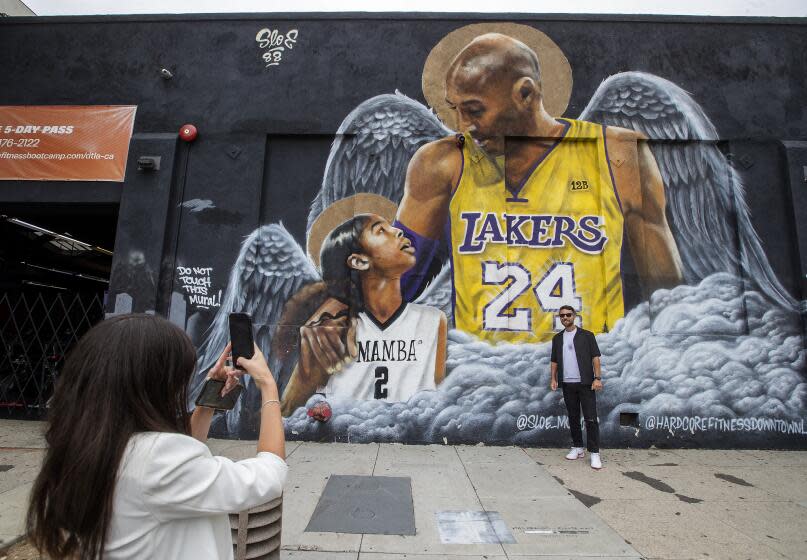 Maria Eastaldo photographs her husband Salvatore Pesante in front of a mural of Lakers legend Kobe Bryant and daughter Gianna