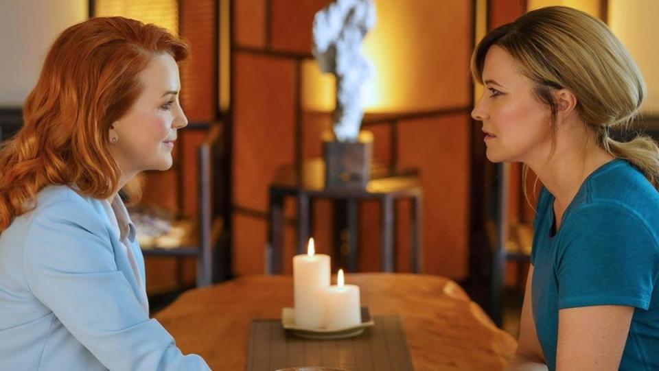 A still from My Life is Murder shows Renee O'Connor and Lucy Lawless facing down over a candlelit table