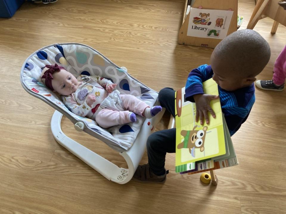 Kinder Academy, in Philadelphia, recently accepted its first infant, Molly, since returning from the initial closures in March 2020. Kinder Academy spent two weeks talking to the toddlers about the baby joining their class and how they would have to be gentle and help us take care of her. Here, Nolan, decides that he is Molly's protector. He loves to tickle her feet and read to her.