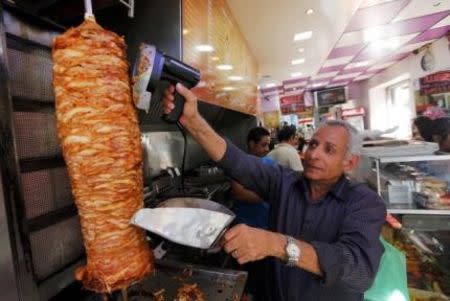 A man cuts meat from a spit as he prepares kebab in a fast-food restaurant in Marseille October 9, 2014. REUTERS/Jean-Paul Pelissier