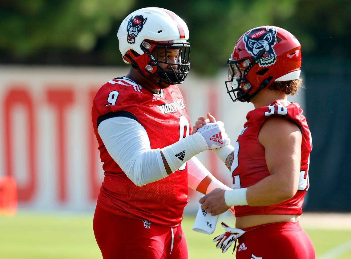 N.C. State defensive end Savion Jackson (9) greets Drake Thomas (32) at the start the Wolfpack’s first practice of fall camp in Raleigh, N.C., Wednesday, August 3, 2022.