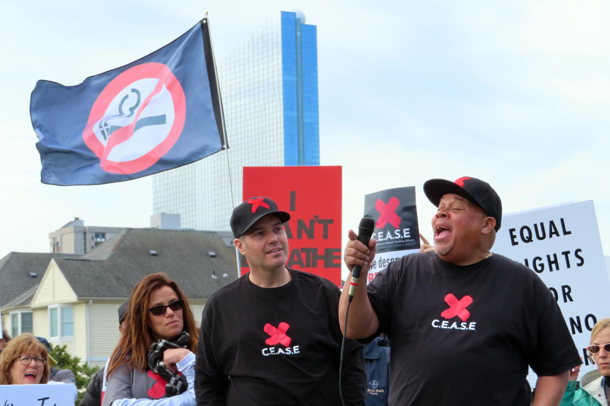 FILE - Borgata casino dealer Lamont White, right, speaks at a rally in Atlantic City, N.J., on April 12, 2022, calling on New Jersey's state Legislature to pass a bill that would ban smoking in casinos. Onstage with him are fellow Borgata dealers Nicole Vitola, left, and Pete Naccarelli, center. A report issued Friday, June 17, 2022, by a Las Vegas gambling research company suggested that ending smoking in casinos will not result in significant financial harm to the businesses. (AP Photo/Wayne Parry, File)