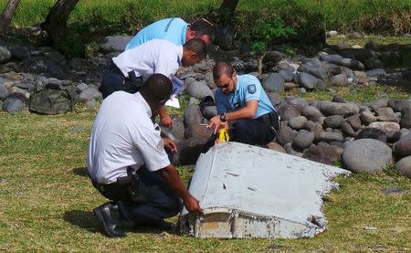 French gendarmes and police inspect a large piece of plane debris which was found on the beach in Saint-Andre, on the French Indian Ocean island of La Reunion, July 29, 2015. REUTERS/Zinfos974/Prisca Bigot