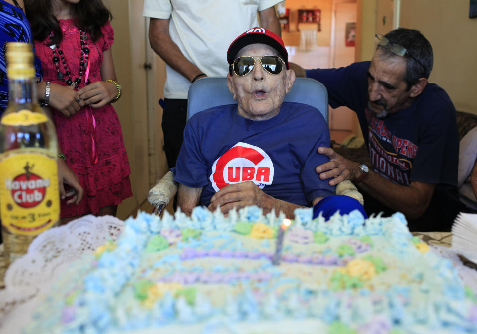 Conrado Marrero, 102, the world's oldest living former major league baseball player, is surrounded by family and friends as he blows out the candle on his birthday cake at his home in Havana, Cuba, Thursday, April 25, 2013. In addition to his longevity, the former Washington Senator has much to celebrate this year. After a long wait, he finally received a $20,000 payout from Major League baseball granted to old-timers who played between 1947 and 1979. The money had been held up since 2011 due to issues surrounding the 51-year-old U.S. embargo on Cuba, which prohibits most bank transfers to the Communist-run island. But the payout finally arrived in two parts, one at the end of last year, and the second a few months ago, according to Marrero's family. (AP Photo/Franklin Reyes)