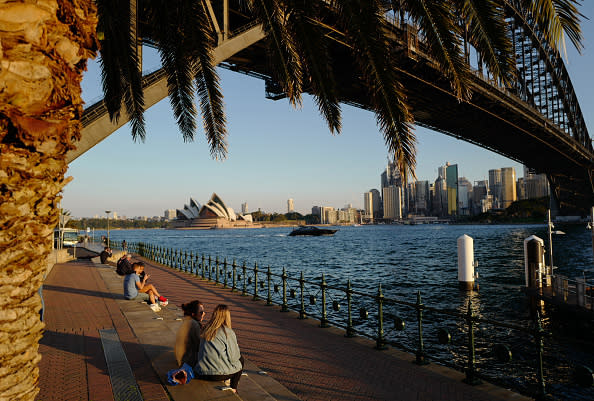 People sit beside the Harbour in the suburb of Kirribilli in Sydney, Australia.