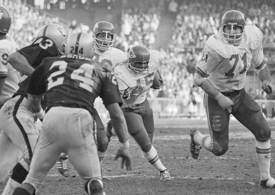 FILE - Kansas City Chiefs' Ed Budde, right, looks to block as Robert Holmes (45) runs for a touchdown against the Oakland Raiders during the AFL championship football game in Oakland, Calif., Jan. 4, 1970. Raiders' Willie Brown is at foreground left. Budde, who spent 14 years playing along the offensive line of the Chiefs and helped the franchise win its first Super Bowl with a victory over Minnesota in 1970, died Tuesday, Dec. 19, 2023. He was 83. The family announced his death through a statement issued by the Chiefs. No cause of death was provided. (AP Photo, File)