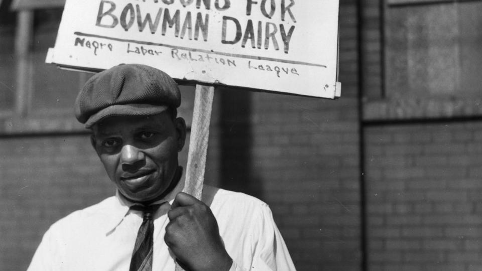 PHOTO: A man holds a sign which reads: 'If Negro men can carry guns for Uncle Sam, surely they can drive milk wagons for Bowman Dairy,' World War II, Chicago, July 1941. (John Vachon/Anthony Potter Collection/Getty Images)