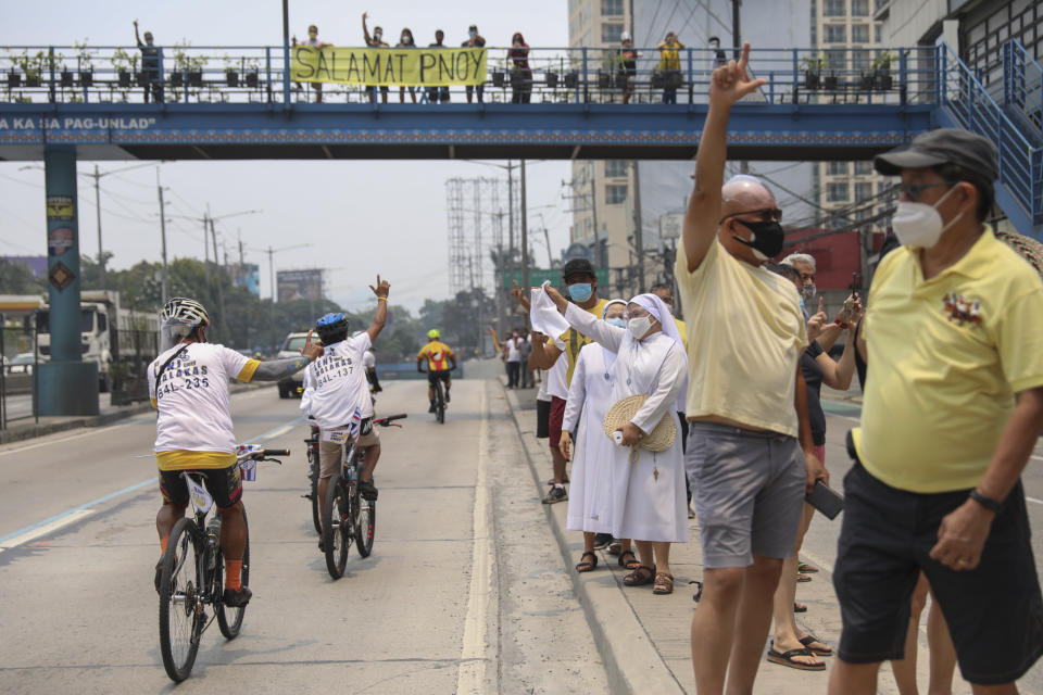 Supporters of former Philippine President Benigno Aquino III flash the "L" sign meaning "Fight!" during a motorcade before his burial in Quezon City, Philippines on Saturday, June 26, 2021. Aquino was buried in austere state rites during the pandemic Saturday with many remembering him for standing up to China over territorial disputes, striking a peace deal with Muslim guerrillas and defending democracy in a Southeast Asian nation where his parents helped topple a dictator. He was 61. (AP Photo/Basilio Sepe)