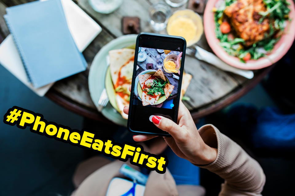 Person holding phone displaying photo of food above a table with breakfast items