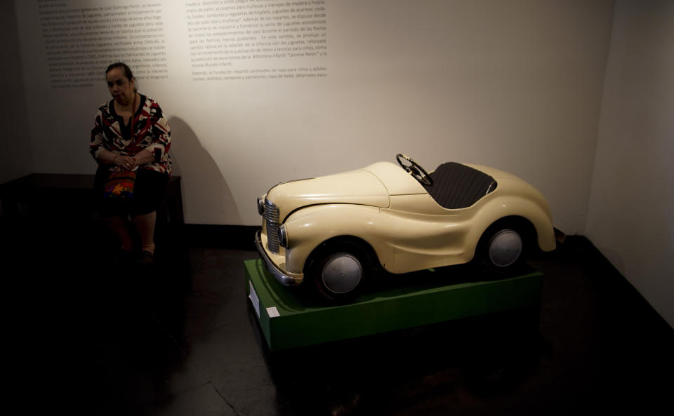 A visitor sits near a toy pedal car of the "Childhood and Peronism, the toys of the Eva Perón Foundation" exhibit at the Evita Museum in Buenos Aires, Argentina, Wednesday, April 17, 2019. To mark the 100th anniversary of the birth of Argentina's so-called "champion of the poor" on May 7, 1919, the Evita Museum in Buenos Aires has inaugurated the exhibit, which displays several dozen of the toys distributed by the party on Christmas Day and the holiday of Epiphany between 1948 and 1955. (AP Photo/Natacha Pisarenko)