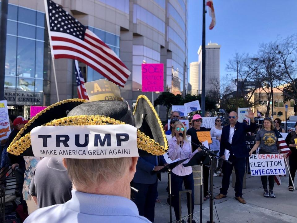 A man with a Trump bumper sticker on his tricorn hat listens to speaker a Defend Florida rally in Tampa on Thursday. Defend Florida has been investigating alleged “voting irregularities” in Florida and advocating for changes to election law based on their findings, but elections officials have dismissed their claims.