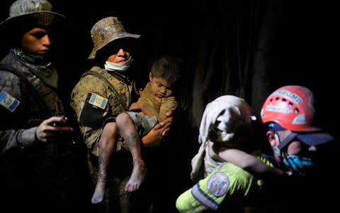 A soldier takes a rescued child covered with ash to a hospital after the eruption  - Credit:  REUTERS
