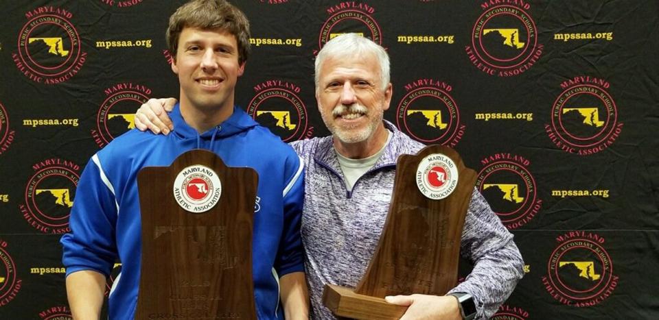 Williamsport coach Matt Shriver, left, holds the first-place trophy, while his father, Smithsburg coach Ray Shriver, holds the second-place award after the Wildcats and Leopards finished 1-2 in the Class 1A boys team standings at the 2019 Maryland State Cross Country Championships at Hereford High School.