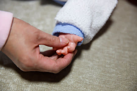 FILE PHOTO: A student at Ayi University, a training program for domestic helpers, practices on a baby doll during a course teaching childcare in Beijing, China December 5, 2018. REUTERS/Thomas Peter/File Photo