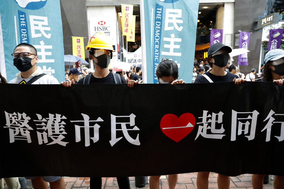 Protesters, some wearing eye patches to show solidarity to a woman reportedly injured in her eye by a beanbag fired by police, hold up a banner that reads: "Medical workers and citizens march together" in Hong Kong Sunday, Aug. 18, 2019. A spokesman for China's ceremonial legislature condemned statements from U.S. lawmakers supportive of Hong Kong's pro-democracy movement, as more protests were planned Sunday following a day of dueling rallies that highlighted the political divide in the Chinese territory. (AP Photo/Vincent Thian)