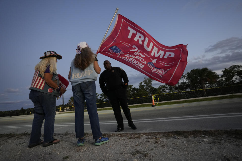 Trump supporters "Maga" Mary Kelley, second left, of Lake Worth, and Kathy Clark of Lantana talk to a police officer as they protest following the news that former President Donald Trump has been indicted by a Manhattan grand jury, Thursday, March 30, 2023, near his Mar-a-Lago estate in Palm Beach, Fla. Trump has been indicted by a Manhattan grand jury, prosecutors and defense lawyers said Thursday, making him the first former U.S. president to face a criminal charge and jolting his bid to retake the White House next year. (AP Photo/Rebecca Blackwell)