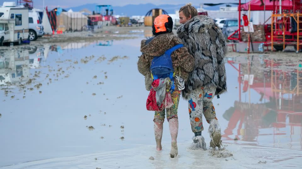 Burning Man attendees walk through the mud on Saturday. - Trevor Hughes/USA Today Network