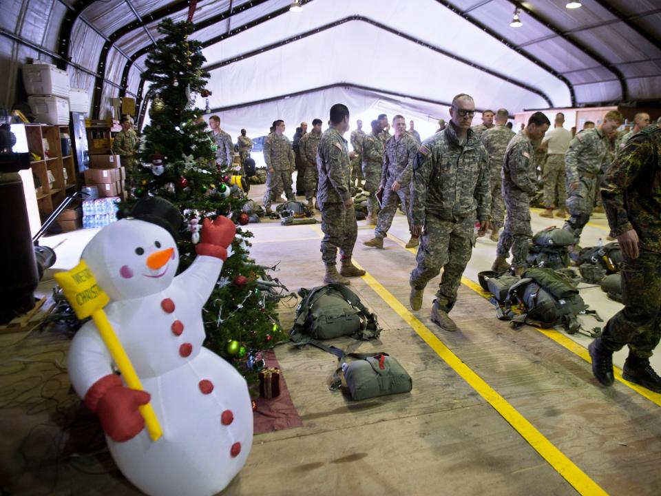 US Army soldiers of the 4th Infantry Brigade Combat Team (Airborne) 25th Infantry Division, part of the NATO-led peacekeeping mission in Kosovo (KFOR), walk past a Christmas tree and a synthetic snowman as they prepare their gear during a US military exercise in Camp Bondsteel, near the village of Sojevo, on December 21, 2014.